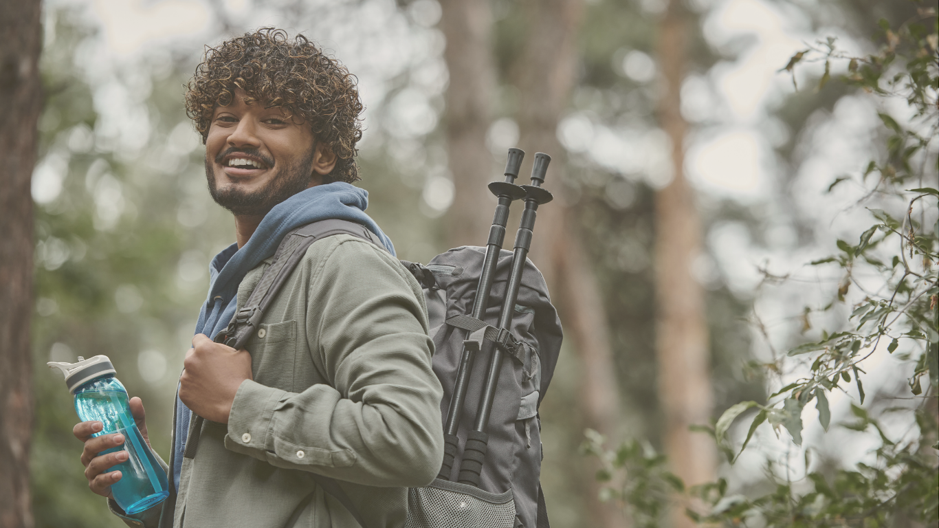 A smiling hiker with a backpack near an RV boondocking site, symbolizing adventure and off-grid travel.
